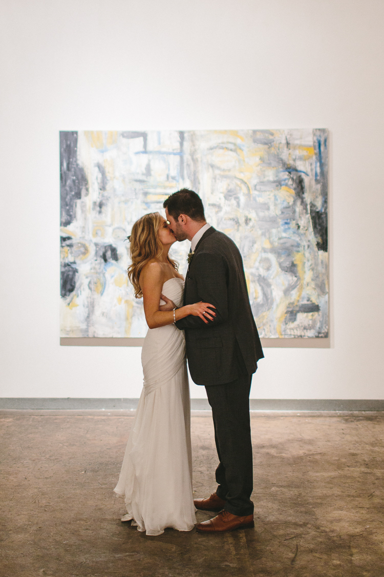 Bride and groom share a kiss at art gallery reception