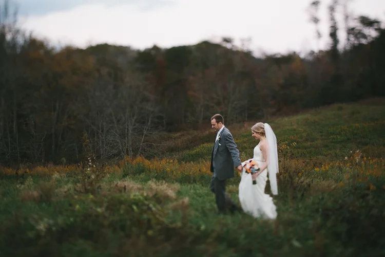 Bride and groom walking through field