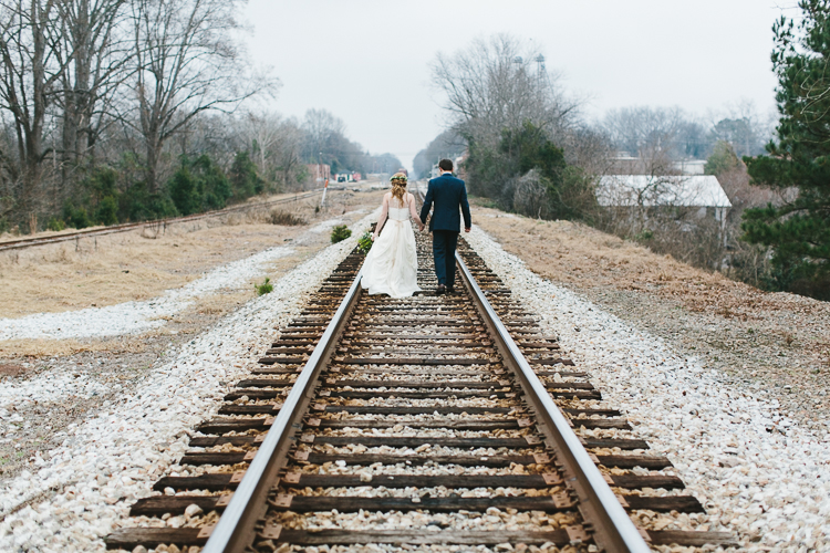 bride and groom walking on railroad tracks