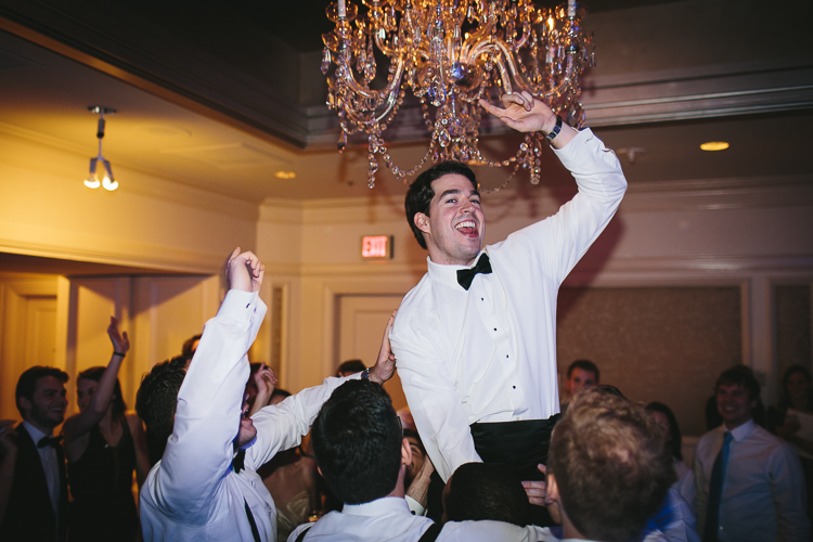 the groom gets lifted up at the wedding reception