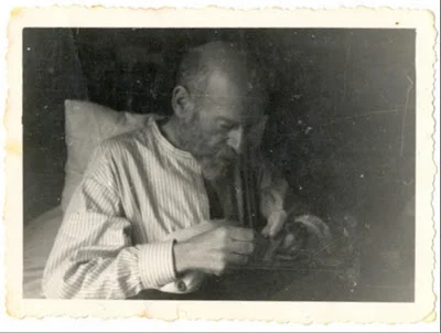 Korczak sewing while sick in bed.