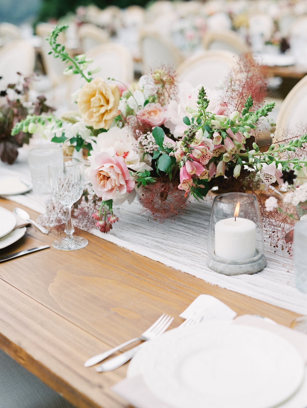  A guest's point-of-view of the tablescape; how lovely to frame conversation and courses with candlelight and a compote of midsummer blooms.&nbsp;  Photo by Michele Beckwith. Event Design by Lambert Floral Studio. 