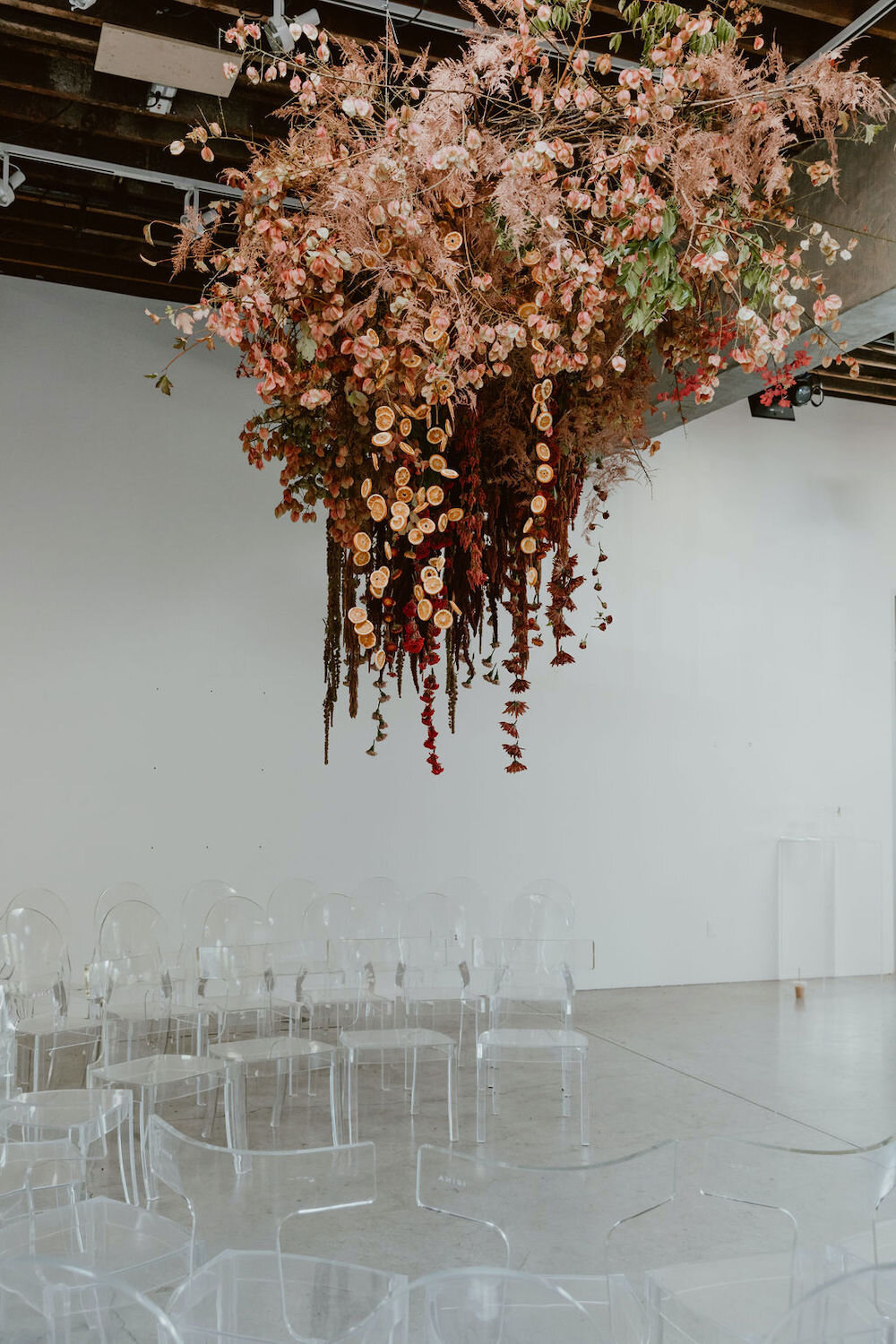  Ellen &amp; Daniel were wed underneath a cloud of vibrant fall flowers and foliage. Do you spy the garland of dried oranges?   Photo by Kait Miller. Event Design by The Gingers . 