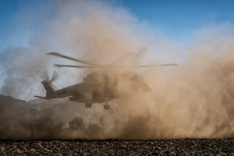 751 Squadron AgustaWestland EH101 Merlin landing high up in the mountains as dust rises up, something known as a brownout. 