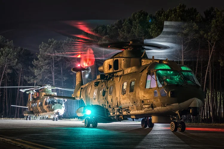Two 751 Squadron EH101 Merlins sit on the tarmac outside of the main hangar at Ovar, the lead cab having just returned from a night mission. 