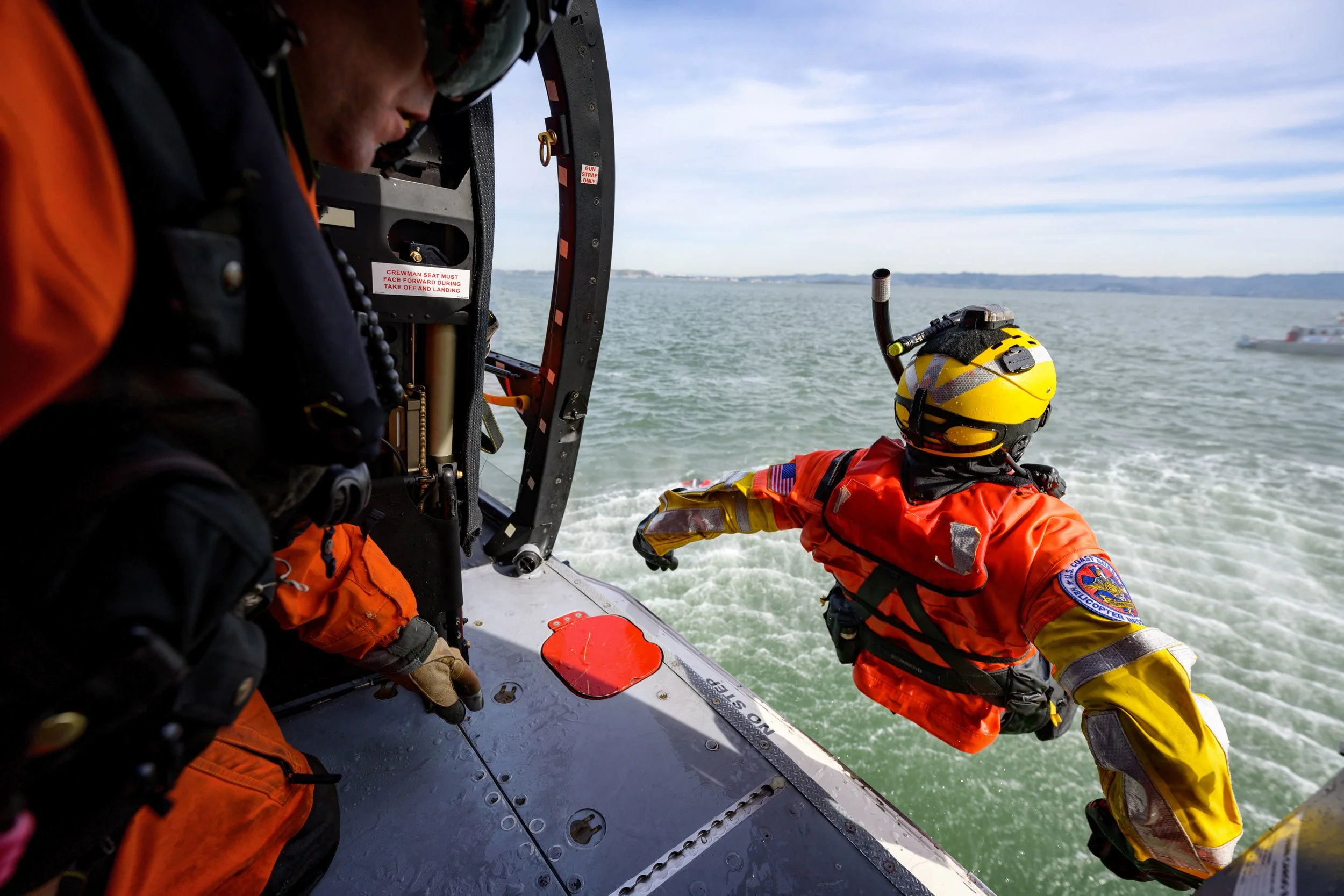 United States Coast Guard rescue sqimmer leaps from an Airbus MH-65E Dolphin