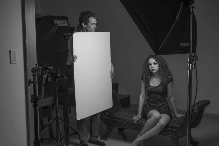 Using a foam core board as a reflector to add fill light. All of the light is coming from the softbox in the right side of the frame. The umbrella is switched off in this image.