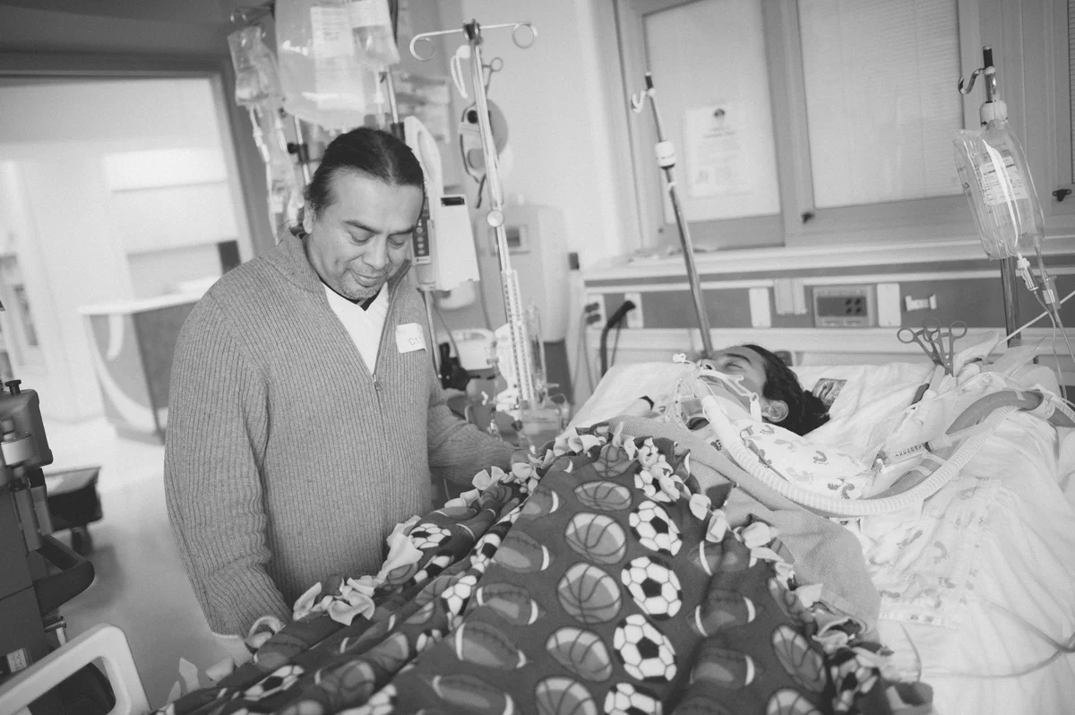 He is praying and holding his son's hand.