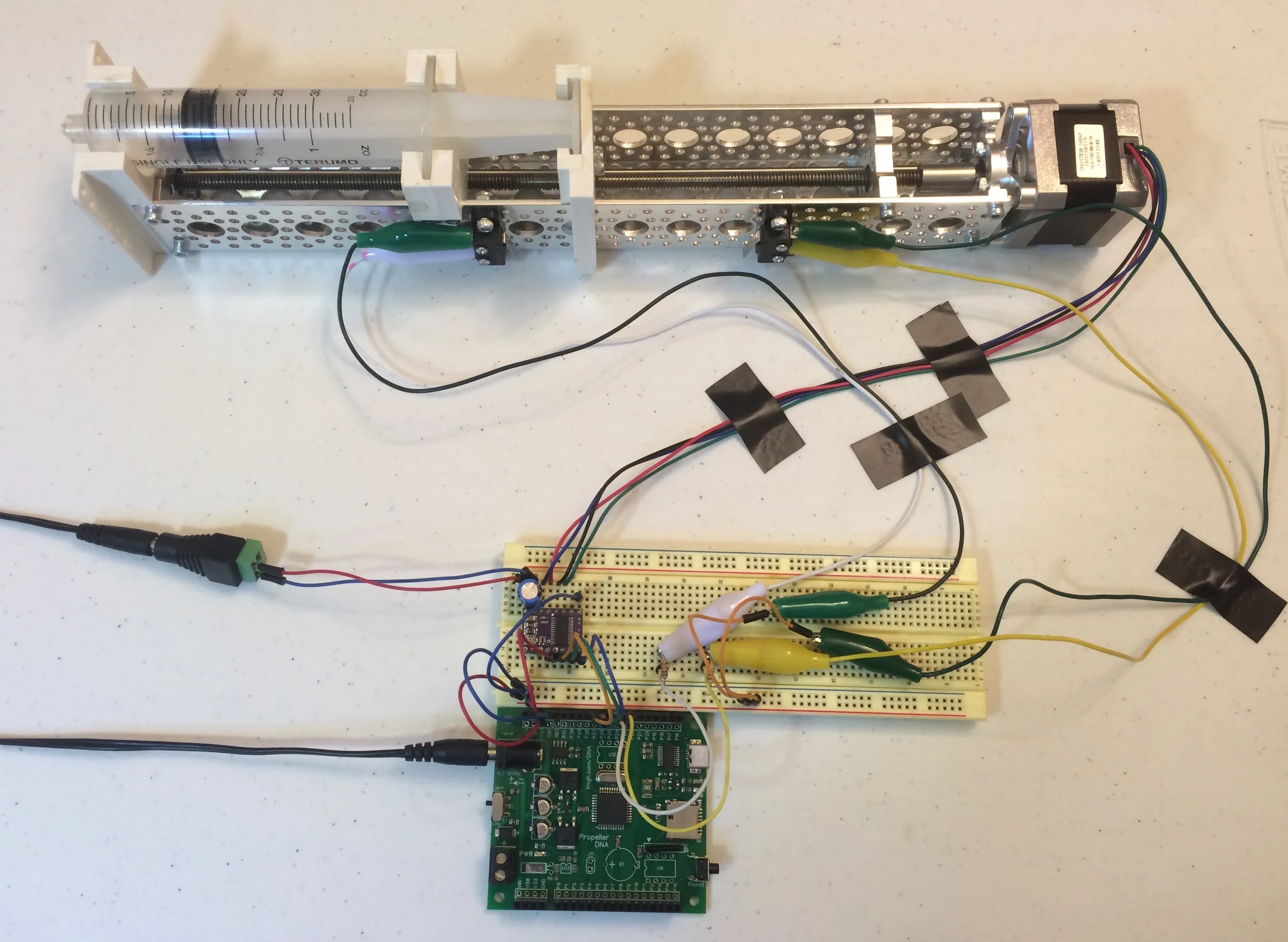SYRINGE PUMP and completed circuit with DRV8825, PROPELLER MICROCONTROLLER, and limit micro switches. IN THIS IMAGE, THE SLEEP PIN ON THE DRV8825 IS NOW CONNECTED TO AN I/O PIN ON THE PROPELLER.