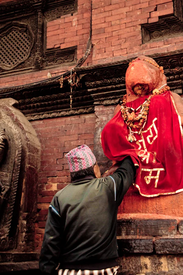 A Nepalese man offers prayers at Patan Durbar Square in Lalitpur.jpg
