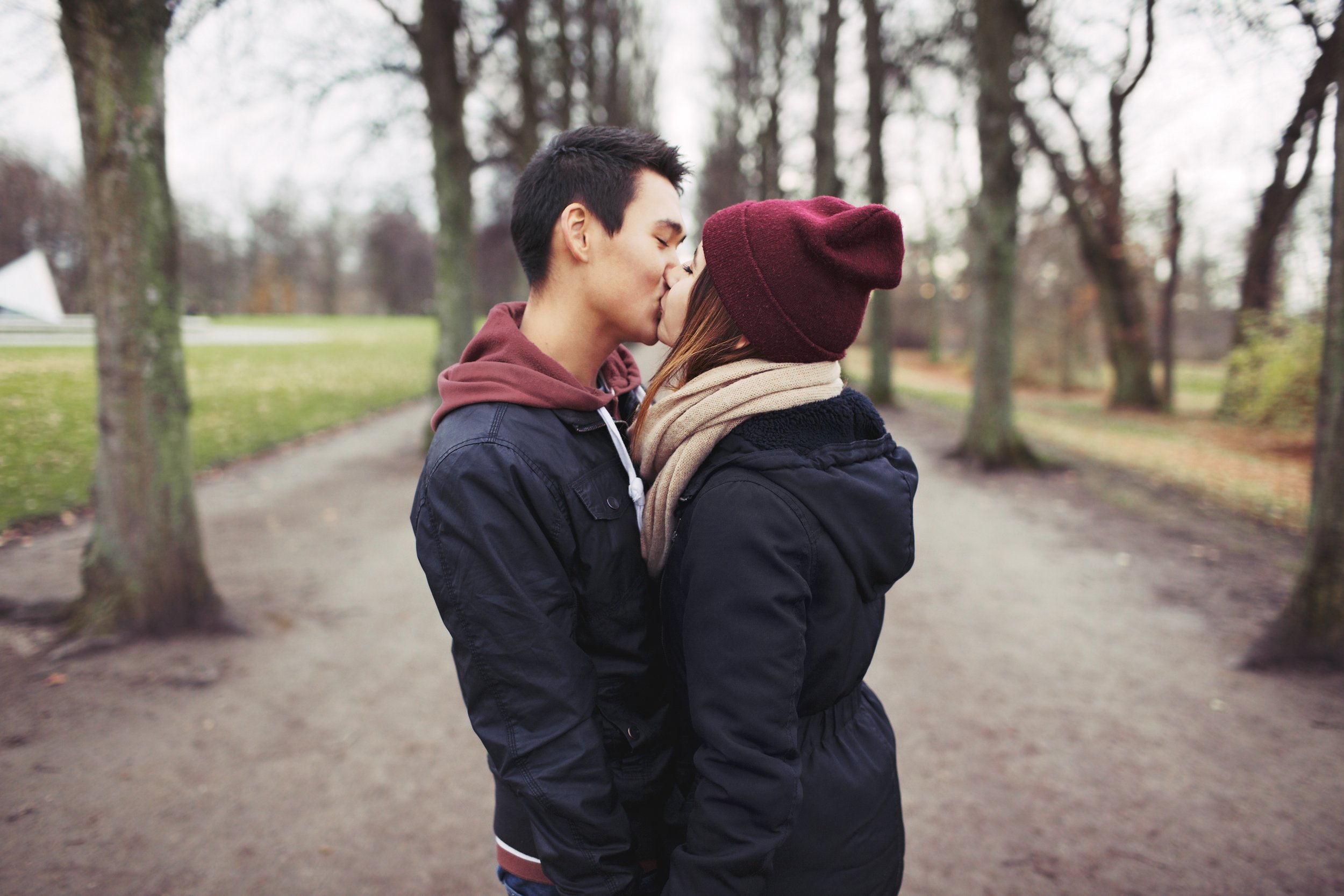 loving-young-couple-kissing-outdoors-in-the-park-mixed-race-man-and-woman-teenage-love-SBI-301327297.jpg