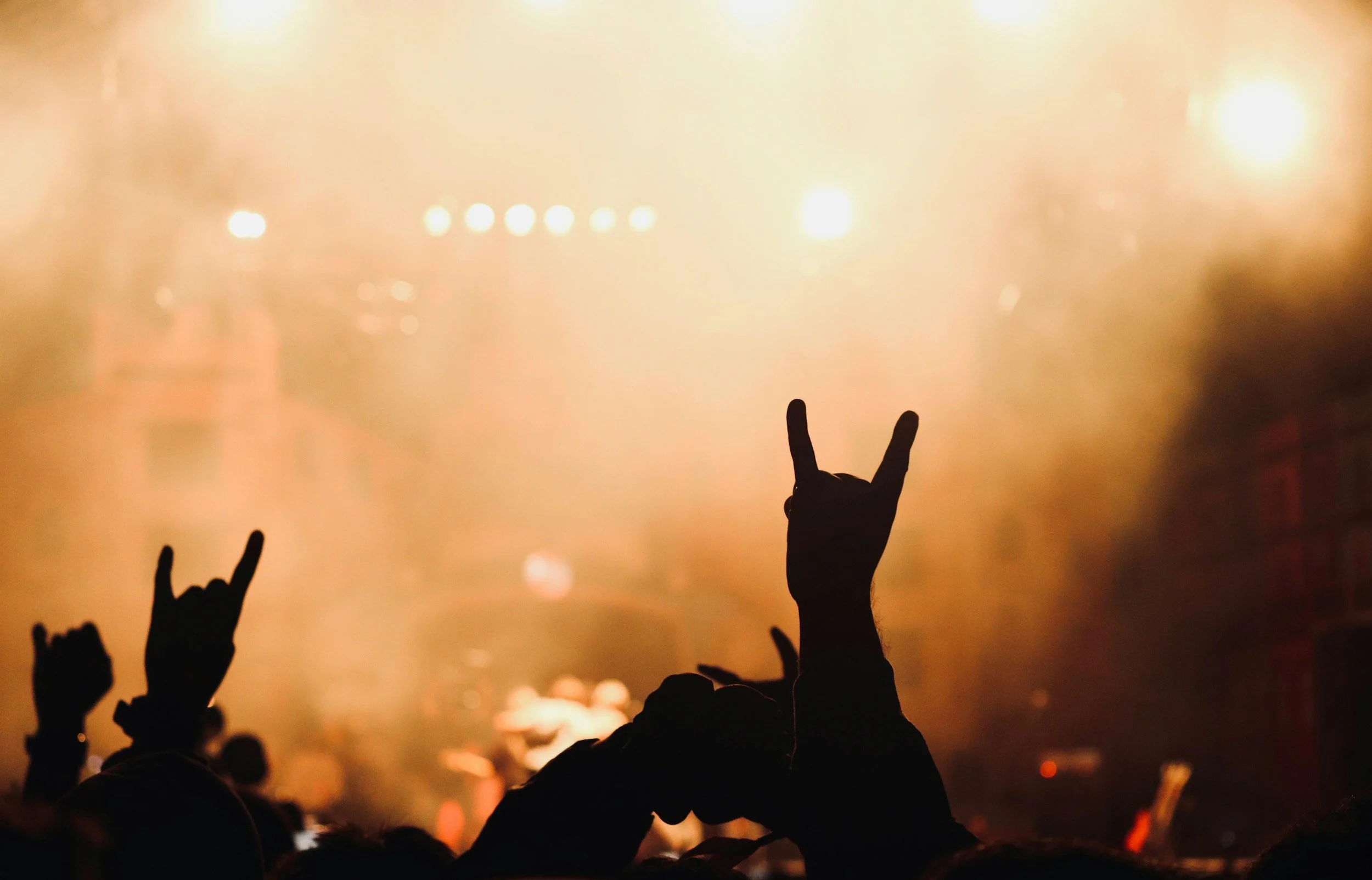 hand stretched up giving the rock symbol before a cloudy stage