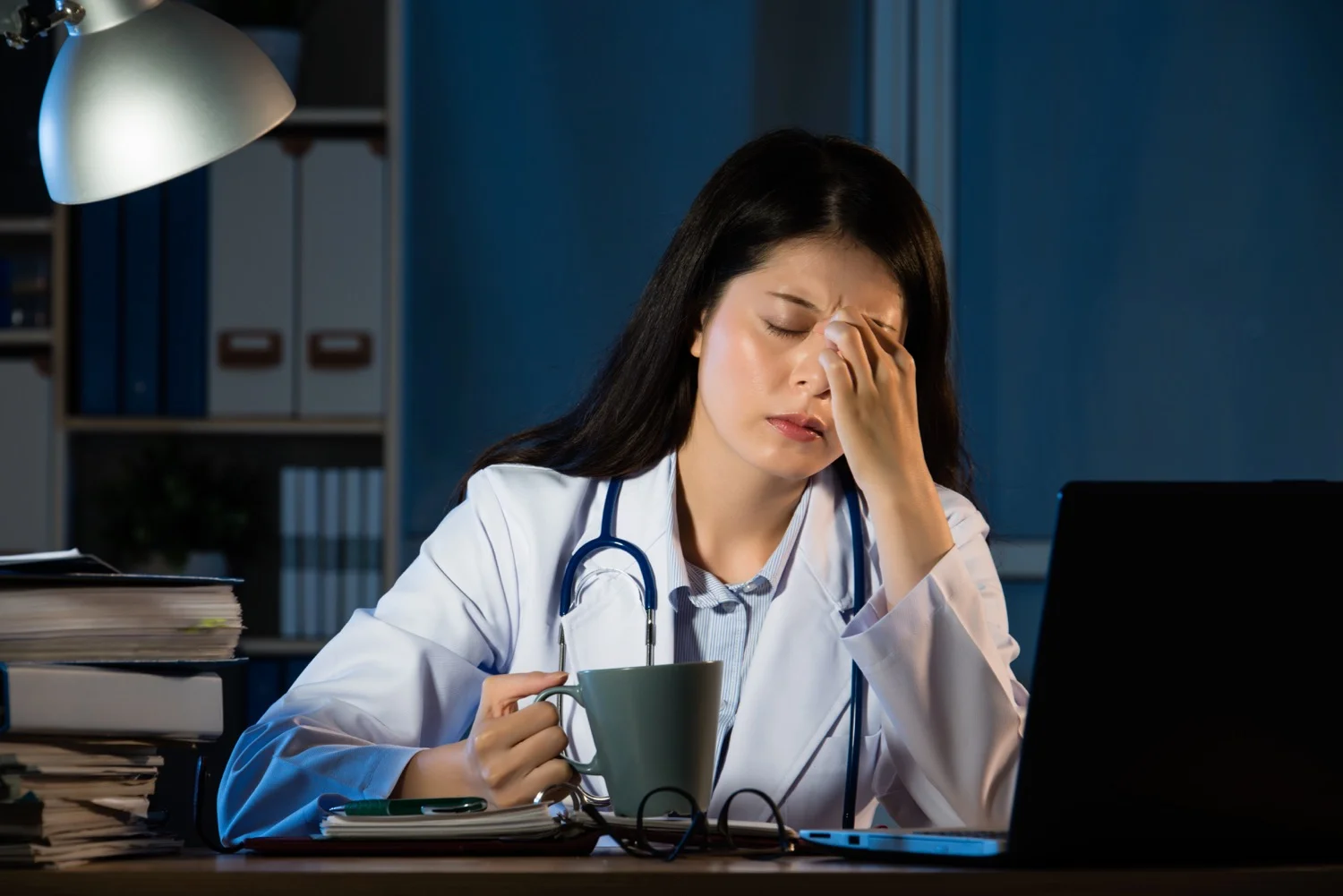 unhappy doctor with headache stressed holding coffee.jpg