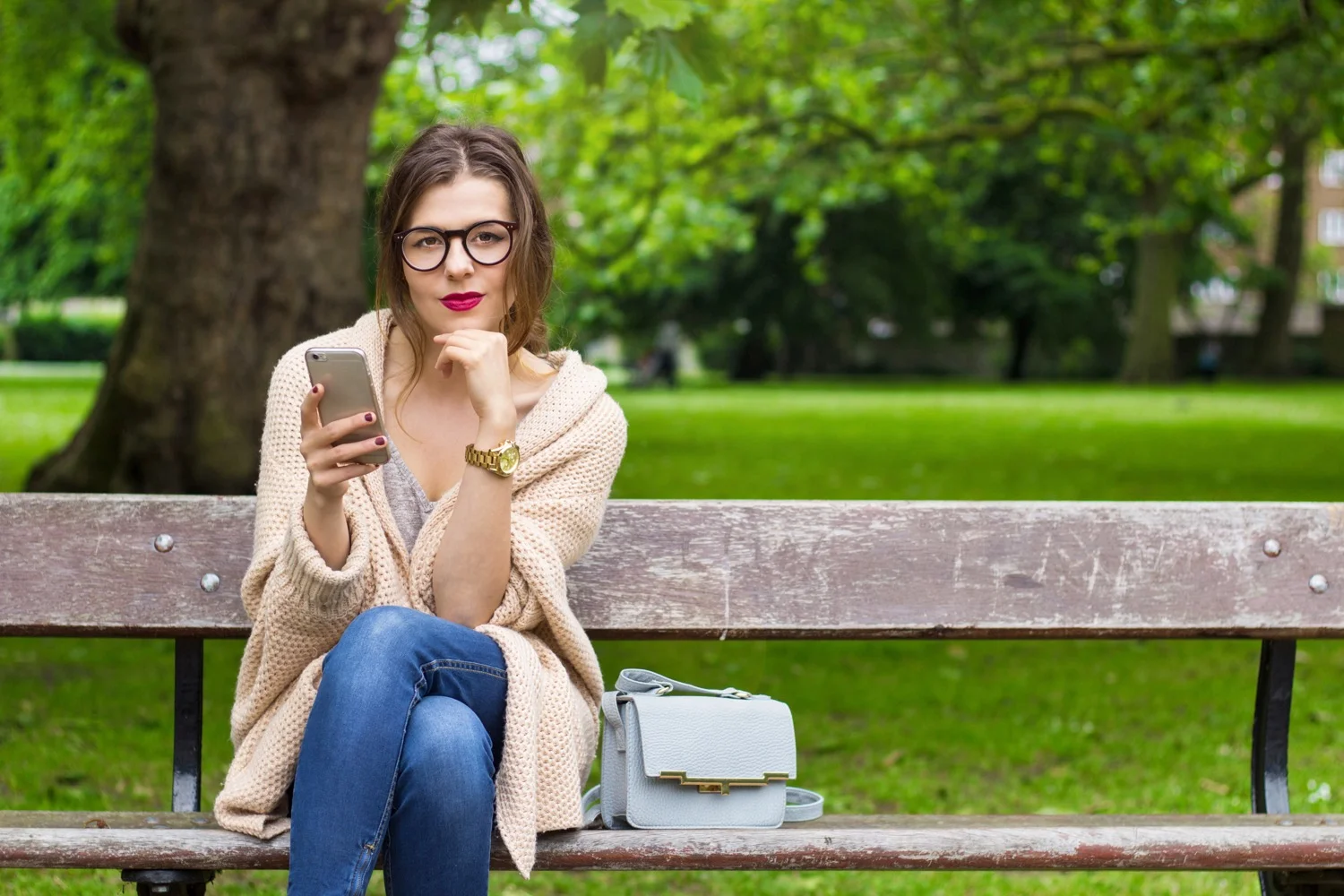 Young woman sitting in the park with phone.jpg