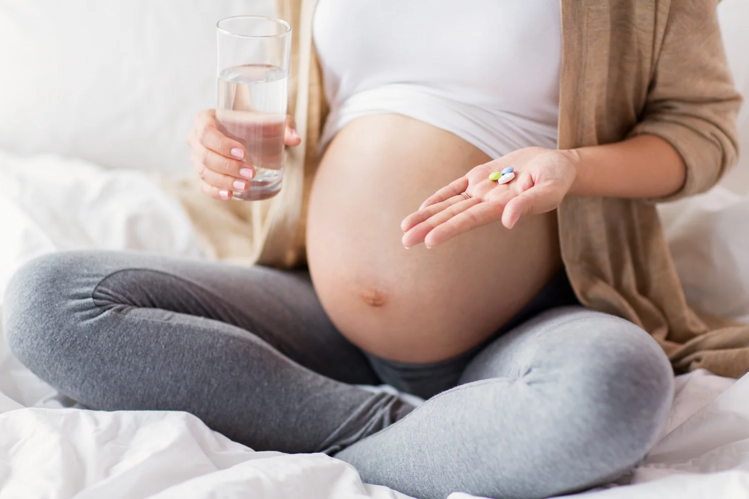 close up of pregnant woman with pills in bed.jpg
