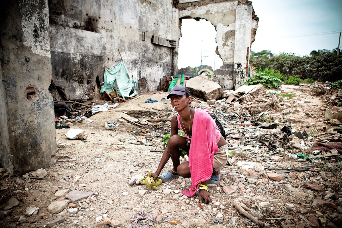 A woman I found care-taking over a plastic doll inside a tiny tent, leaves her living space to pose for the camera. Barranquilla, Colombia 2014.