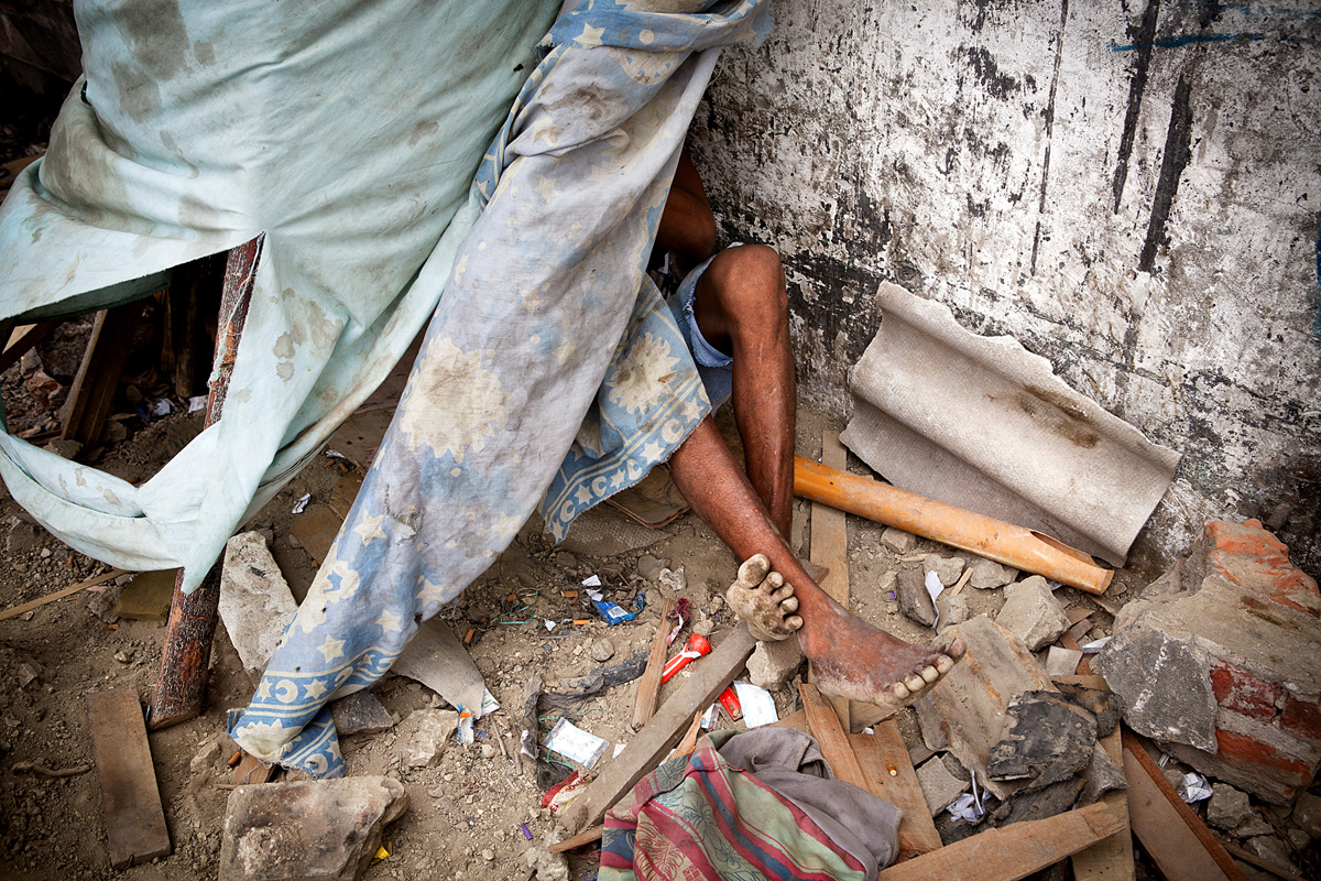 A person chill in his tent is completely oblivious to my photographing outside outside. Alcohol pads surround his feet which can suggest IV use. Barranquilla, Colombia 2014