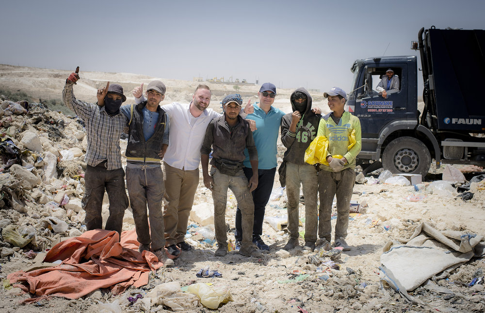 Timothy Bouldry and Antonis Mavropoulos pose with Syrians at the Al Ekaider dumpsite in Irbid, Jordan.