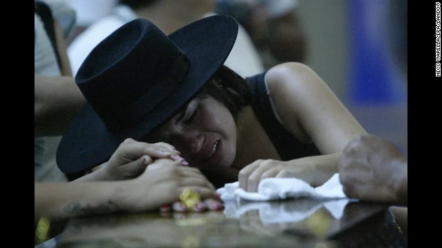 A woman weeps on a coffin as relatives of the nightclub fire identify victims.