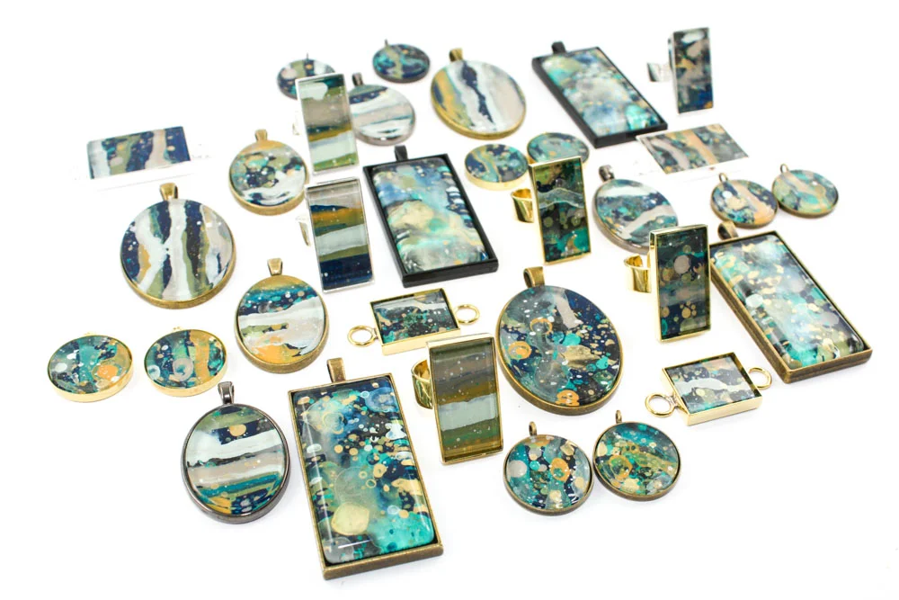 These jewelry pieces are acrylic and glass that I splatter painted on the backside - I made these a few days after Day 16's challenge (the "seriDRIPitous" pendants). This new series will launch soon!