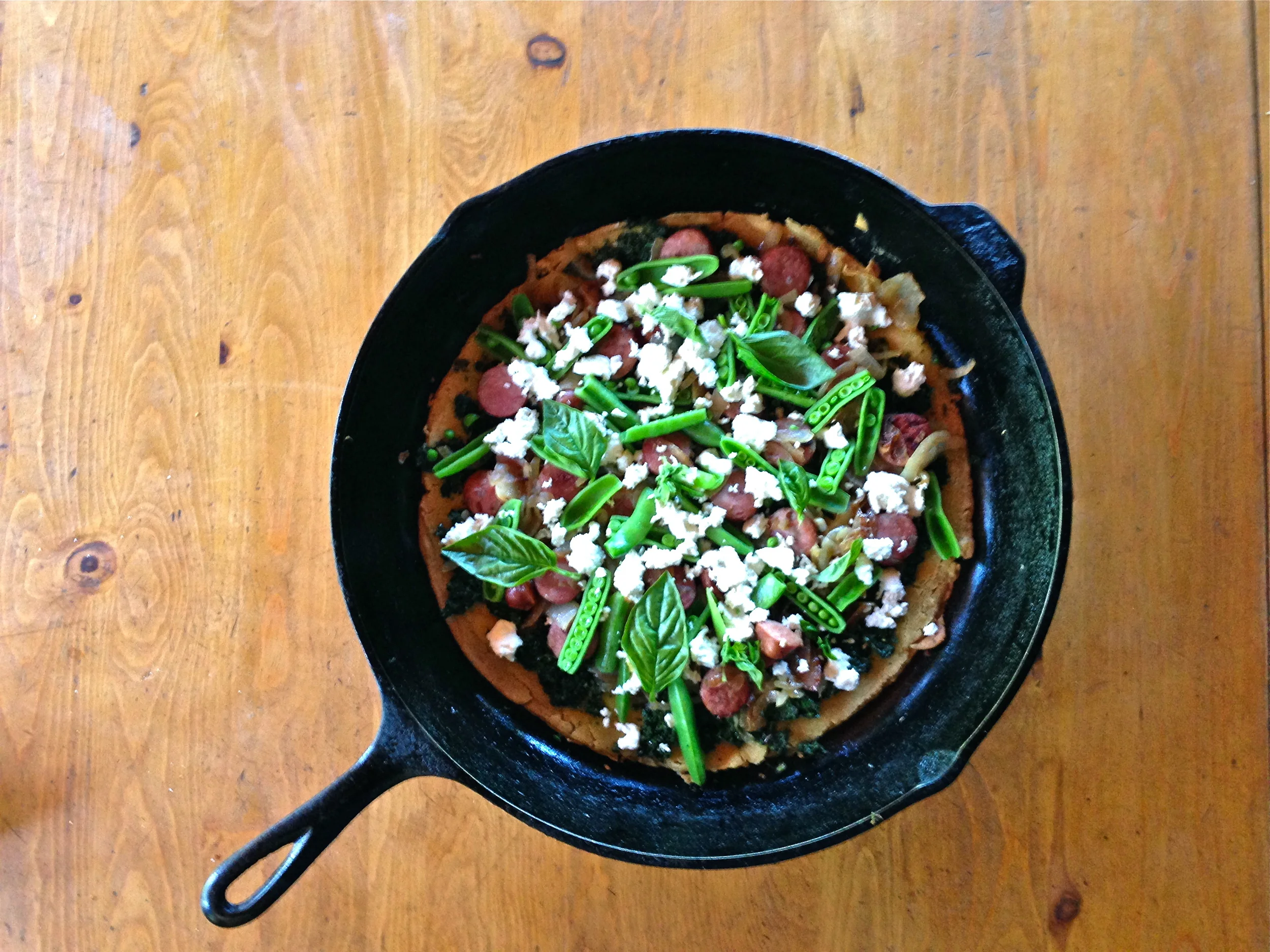 Skillet Socca with summer pesto, sausage, snap peas, basil and fresh chèvre 