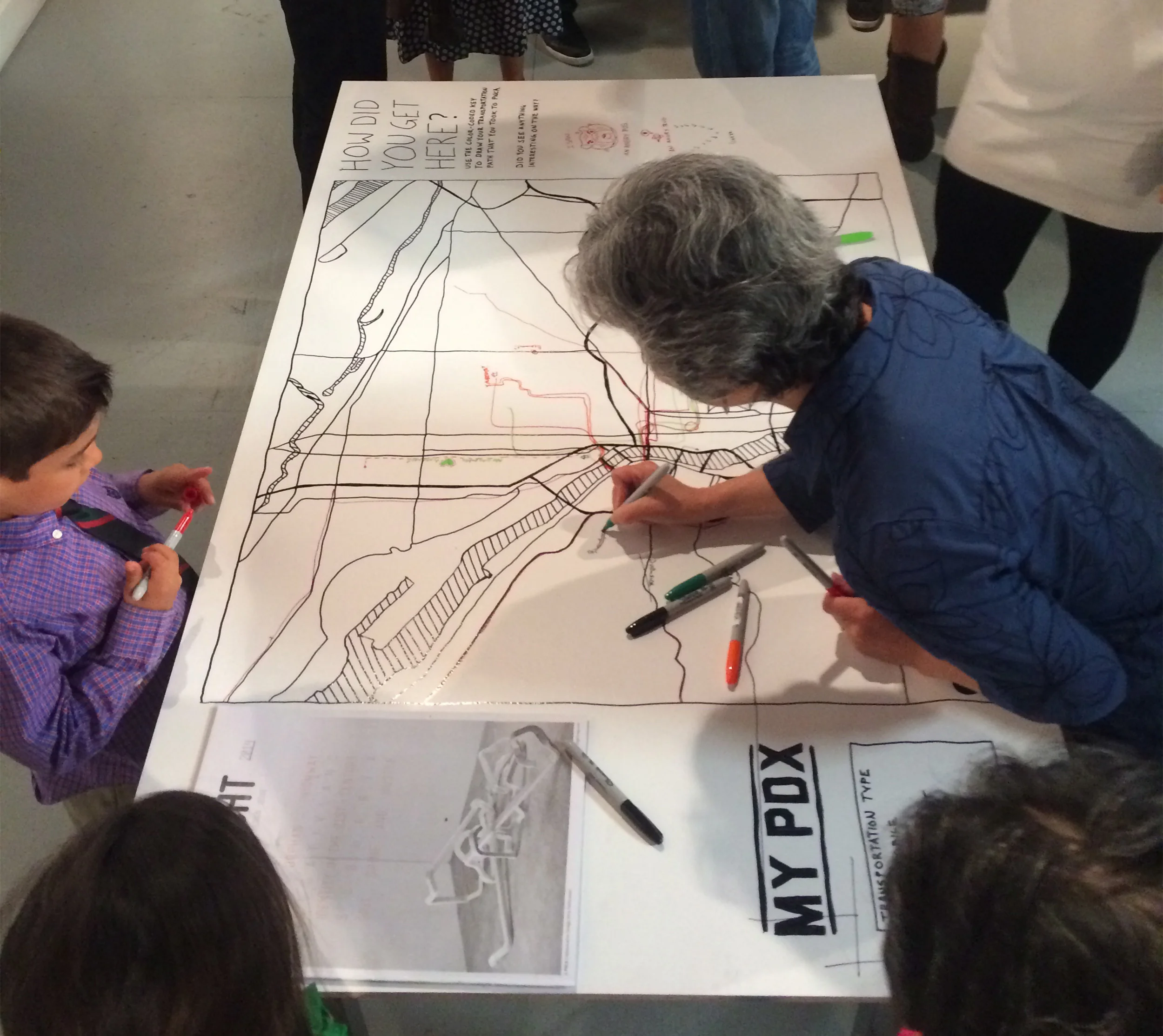 Visitors drawing their path to the exhibition on table top map at the opening