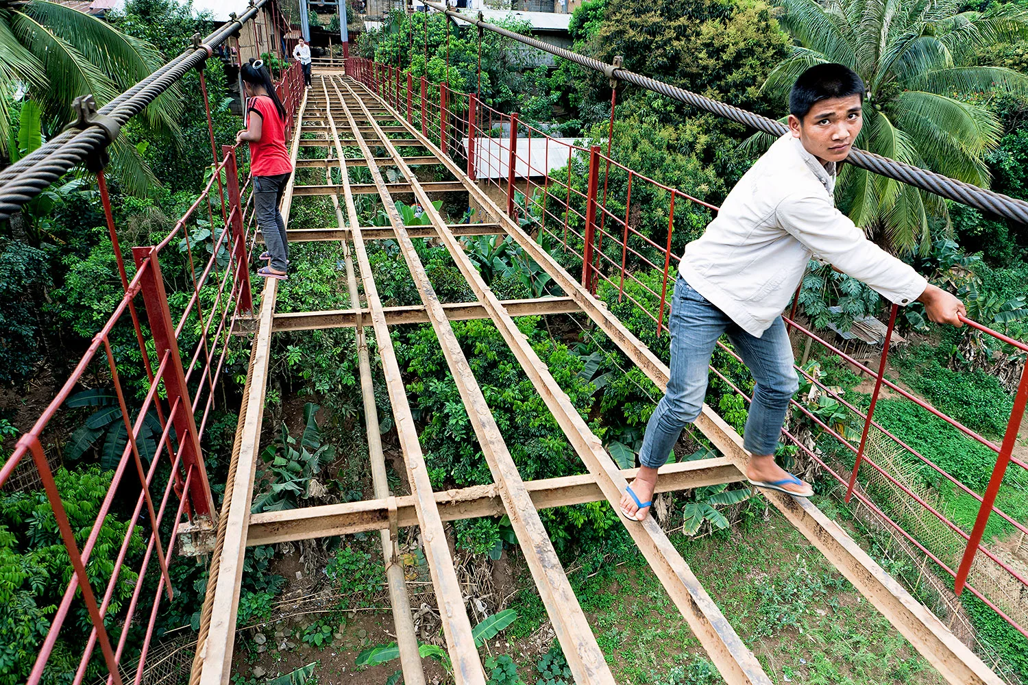 Kids cross an unfinished bridge connecting two parts of their village - Muang Khua, northern Laos