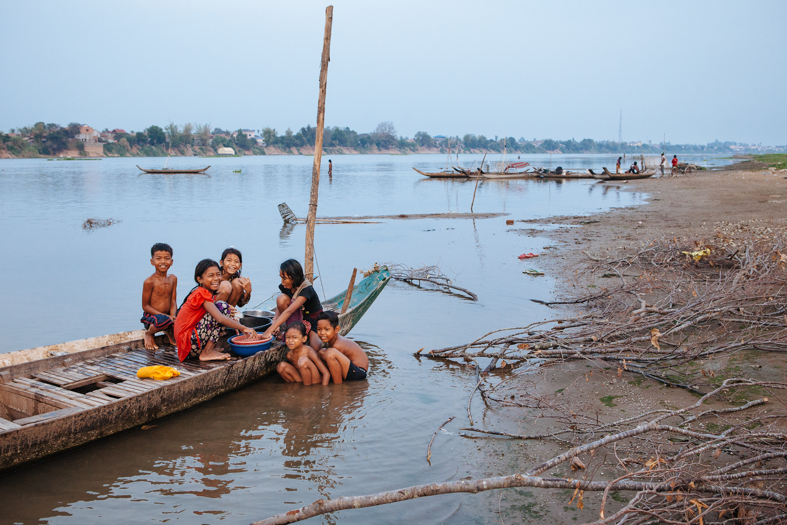 Community children in a riverside village play and do chores at dusk.