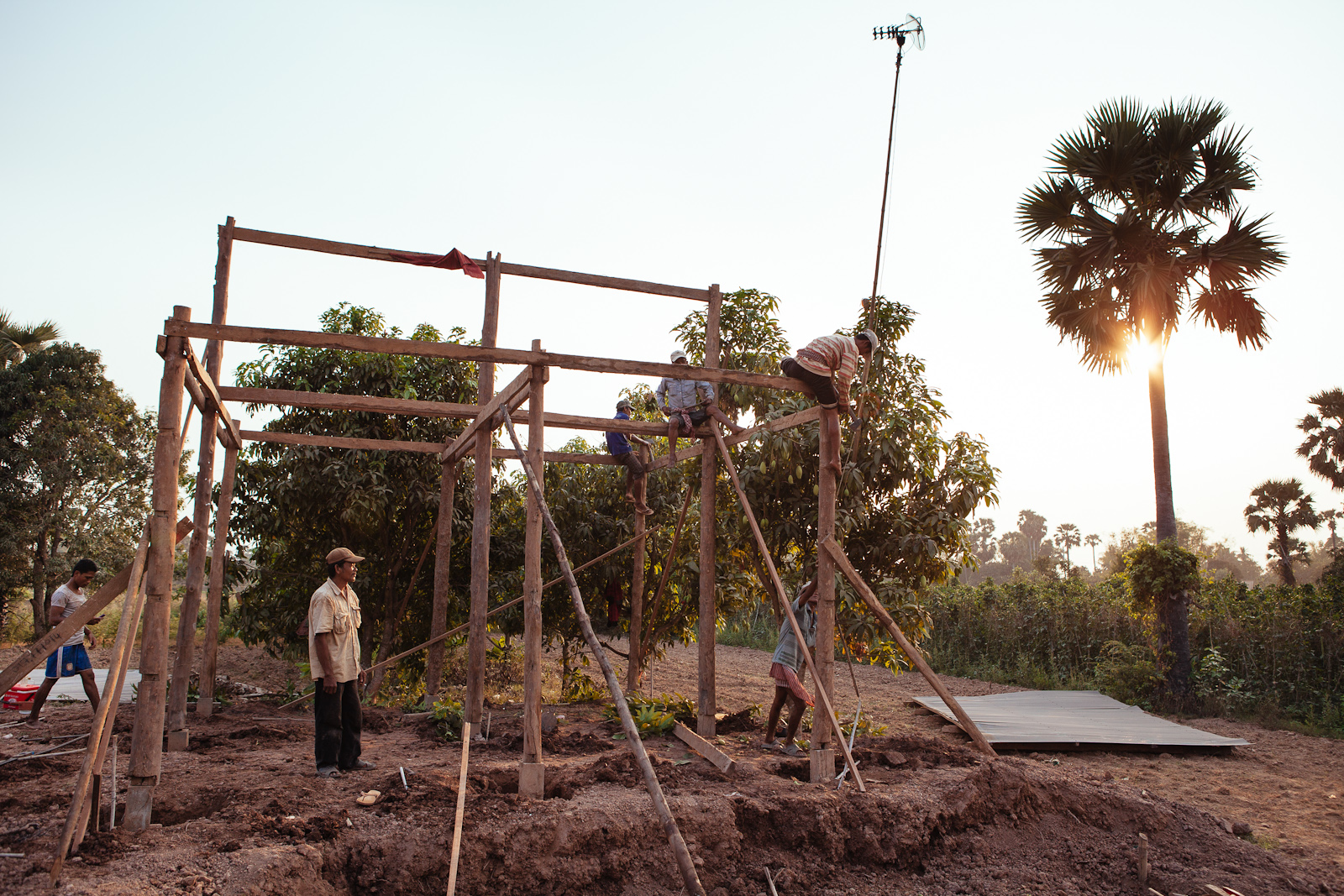 Local men in a remote village work together to build a simple house.