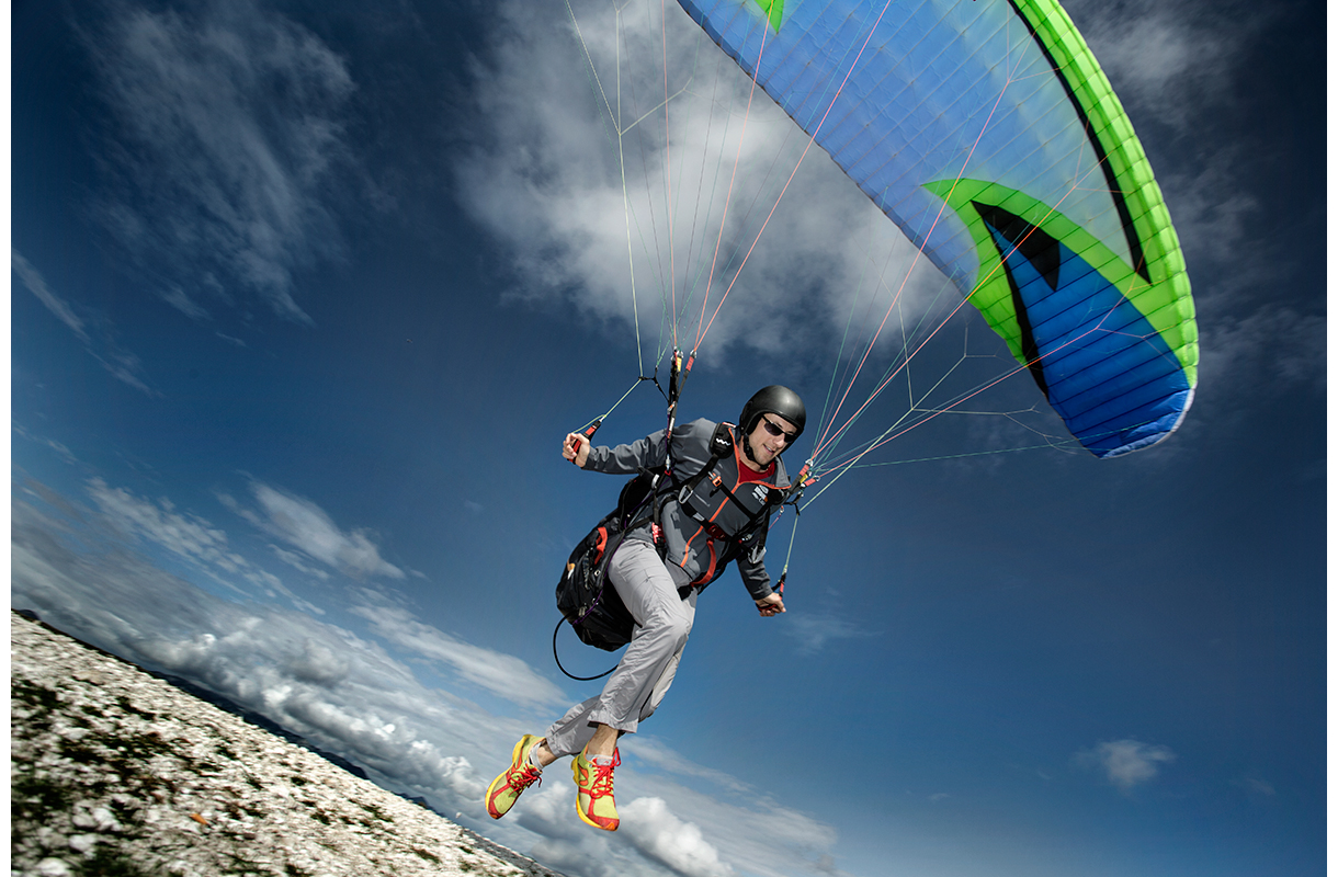 Paraglider riding the thermals on the ridge above Meduno, Italy.