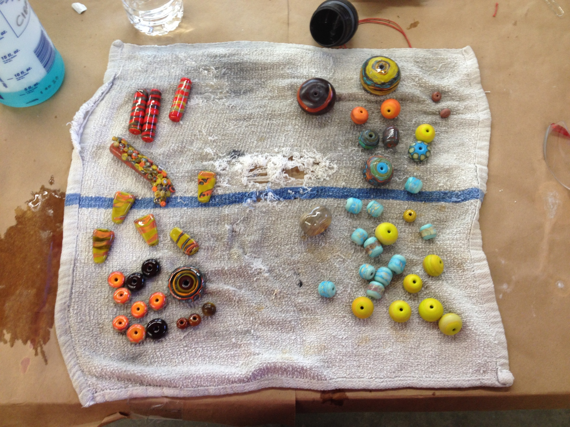 My output after my second day. The stuff on the right had been etched to remove the default glassy shine. Amy says that she can't even think about using her beads until they have been etched. The boot shaped bead on the second row on the left is my roll-up. It came out weird to my eyes, but Amy and Carmichael encouraged me to go with it anyway.