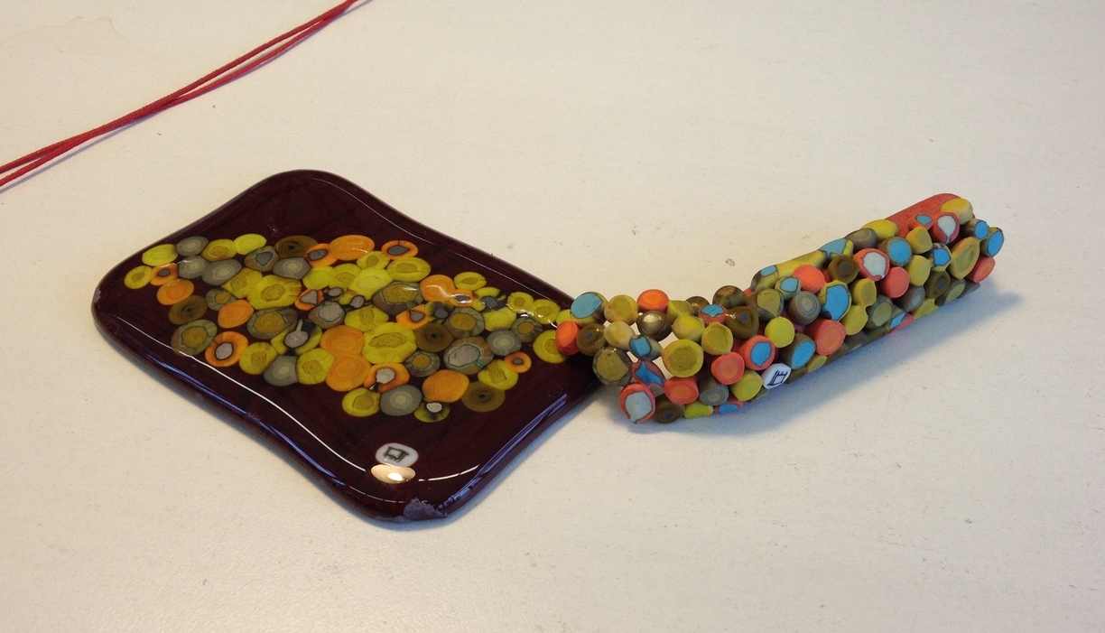 This is my roll-up bead resting atop the fused glass piece I made. It looks like the bead is escaping flat land, no? Notice the Penland logo murrini Amy made and gave to us to use.