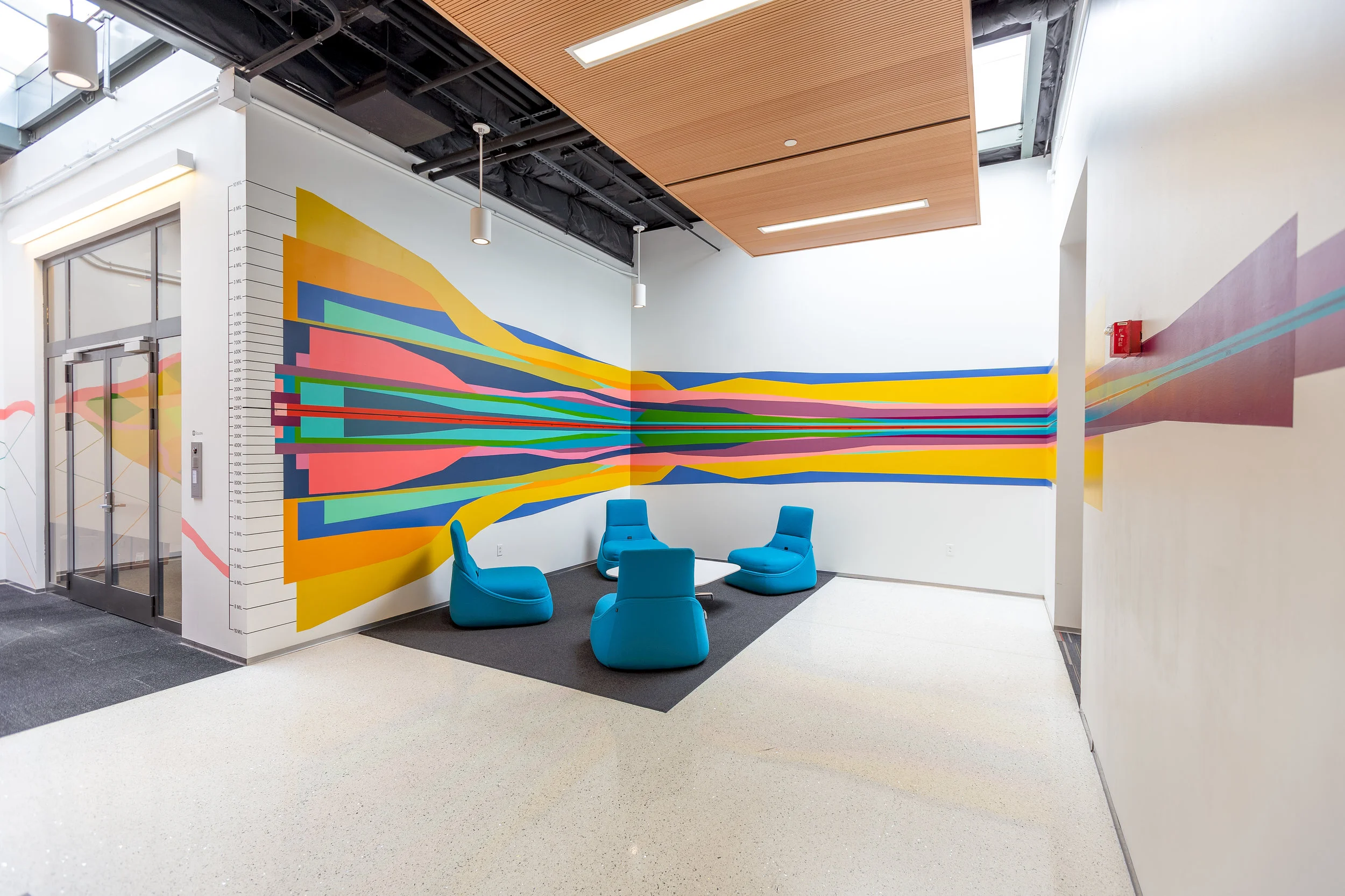 Photo by Jacob Berkowitz This mural is a reflective line graph that visualizes population data from our sister cities. Each city is represented by a color and is layered to show the increase and decline of population from the present to the 1700s. A key on the left shows the population size and the timeline is along the x axis that wraps around the space.