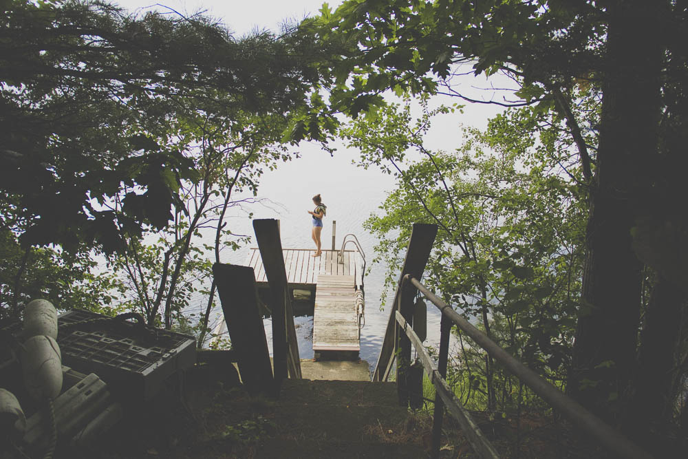 A young woman prepares for a swim on a dock.