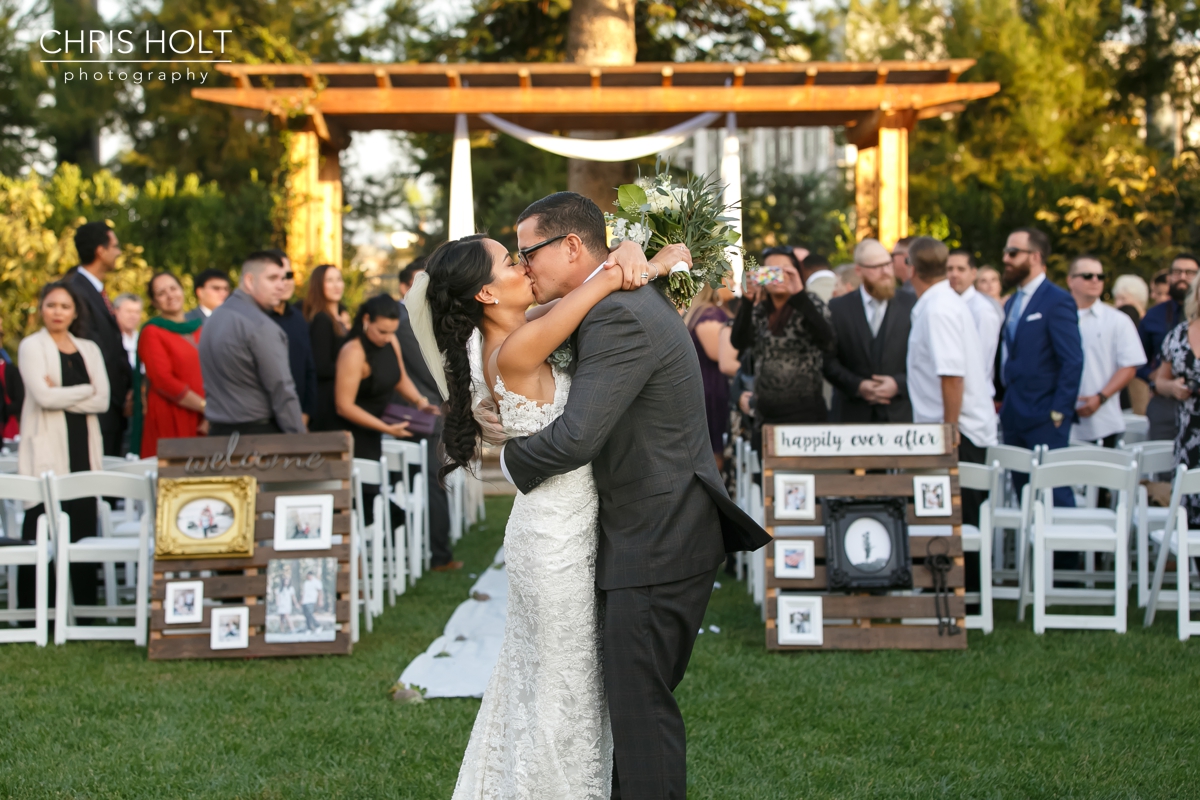 Bride and Groom kissing at the end of the aisle