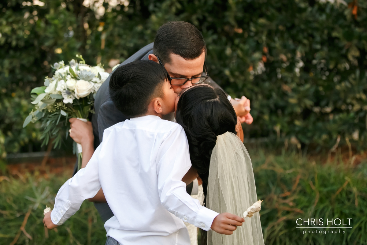 Bride Groom and Ringbearer hugging and kissing as a new family