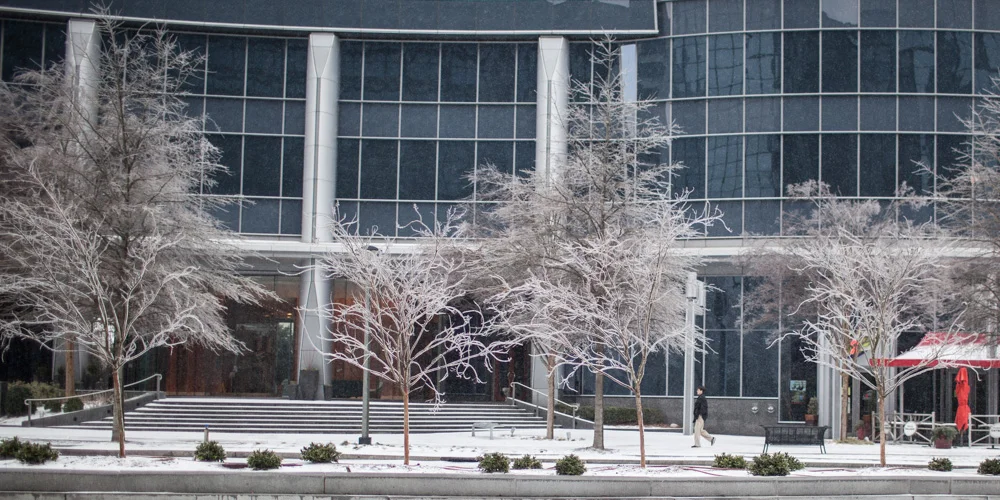 An urban, wintry landscape, punctuated by a walker.
