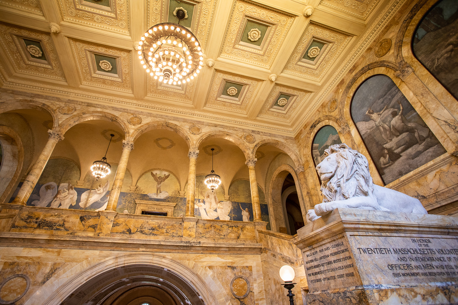 A side view of one of the lion sculptures and the grand chandelier.