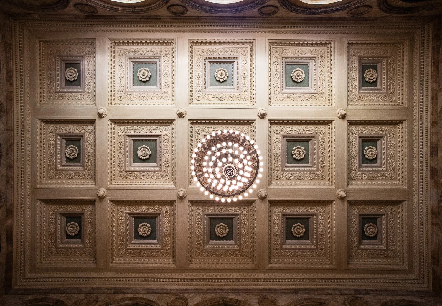 A view of the double coffered ceiling and the great chandelier above the grand staircase in the Boston Public Library.