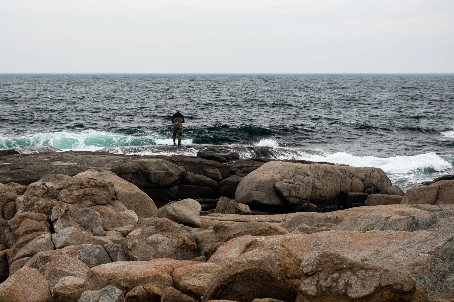 A lone fisherman on the rocks at Nubble Point in York, Maine.