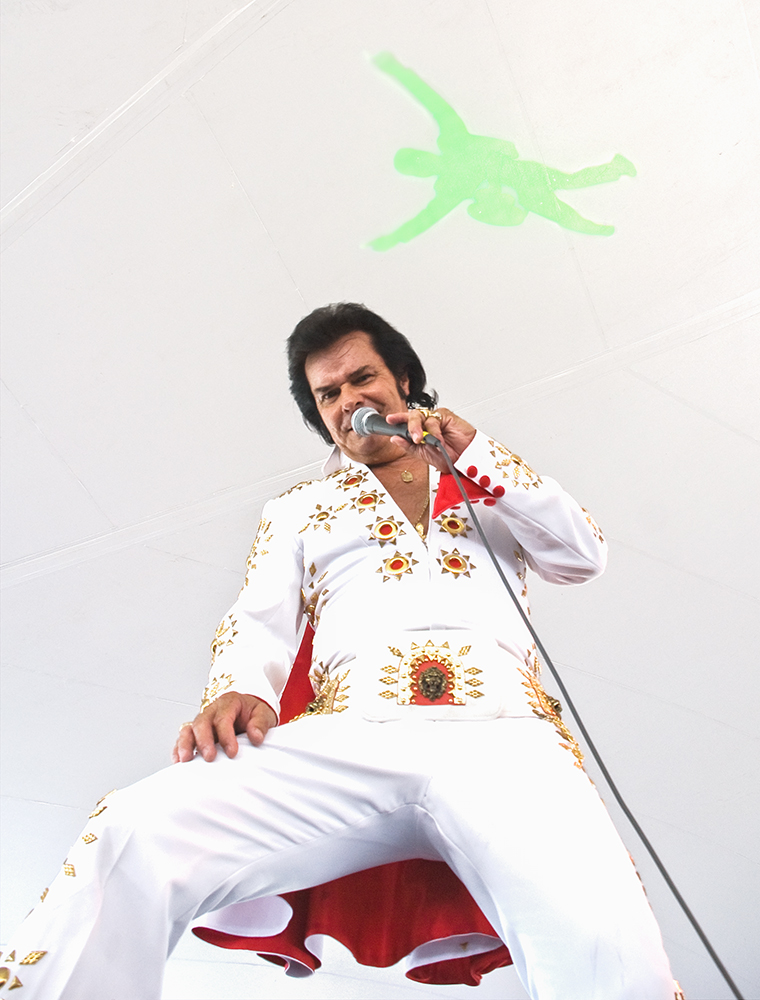 Impersonator of the King in his later years, under the big tent and neon green iconic silhouette on the ceiling. 