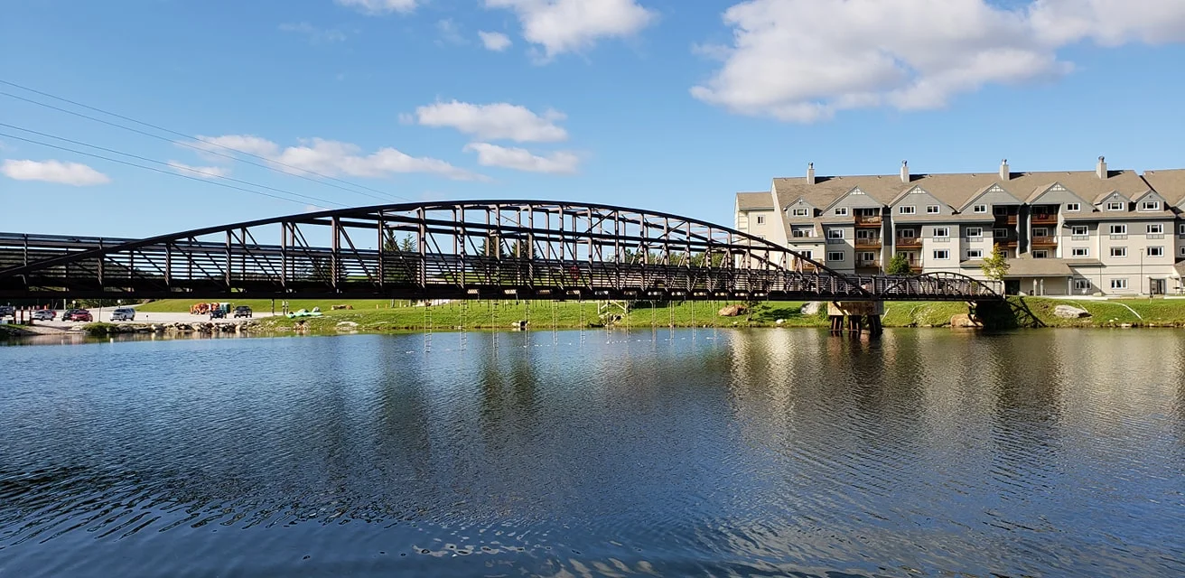 Swim out to the ladder, climb up and swing across the ropes under the bridge and hit the bell on the other side.
