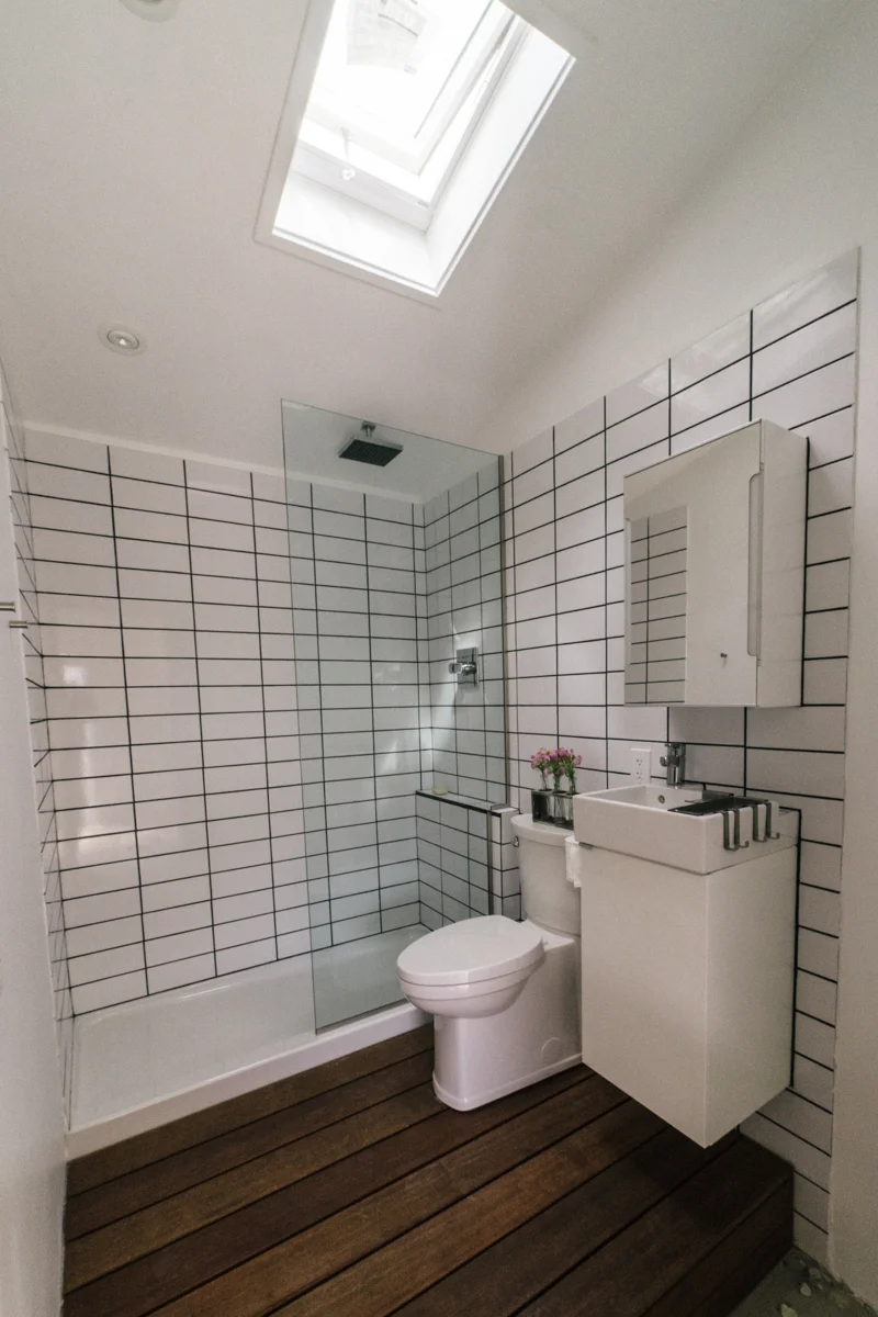In the bath, a deck feature lends a spa-like feel. An operable skylight and white colors make the bathroom clean. 