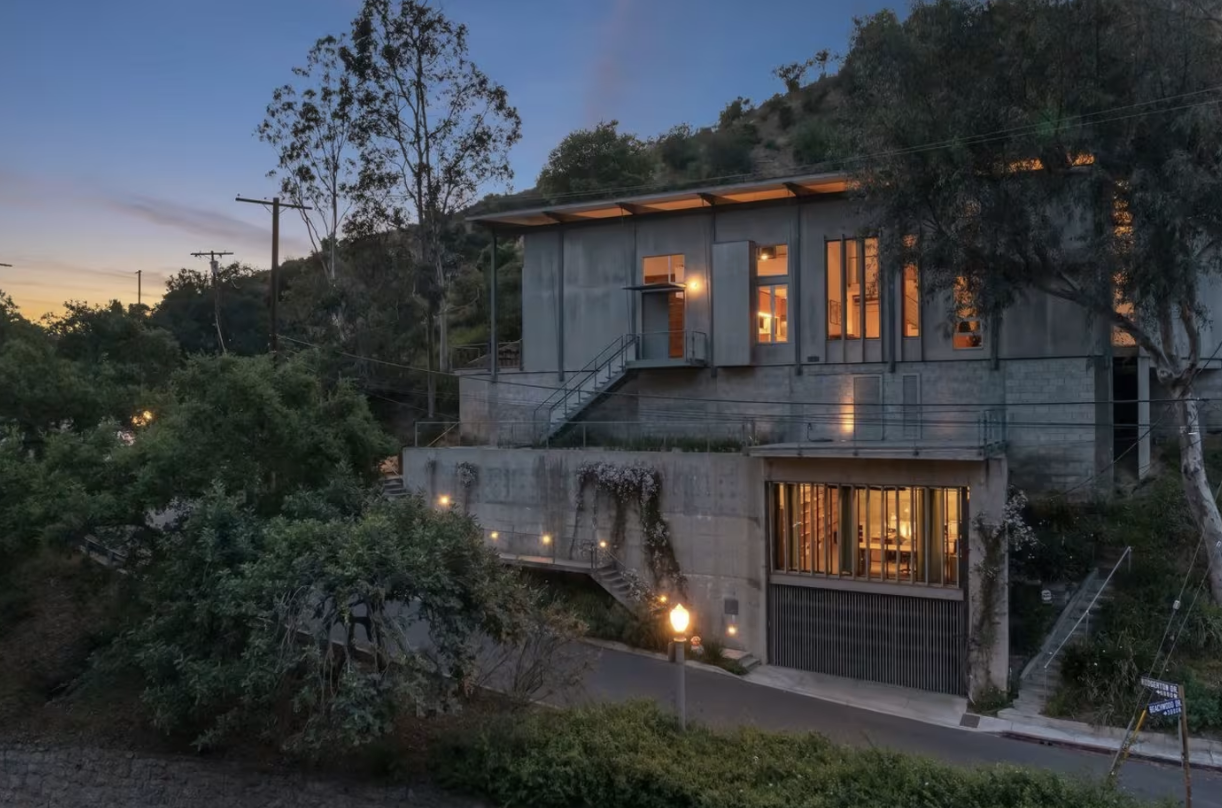 A Los Feliz hillside home perched on a slope above the basin, with retaining walls and a terraced lot below the house.