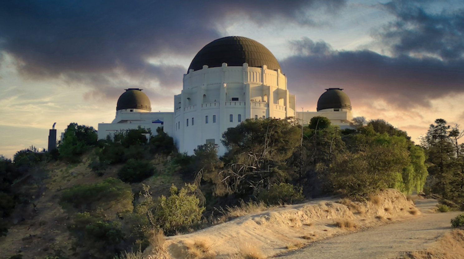 Griffith Observatory above the Los Feliz hills at golden hour, seen from a park-adjacent street in Los Feliz, Los Angeles.
