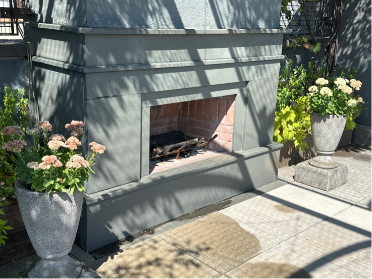 Penthouse rooftop garden designed installed and maintained by Halsted Welles Associates featuring a built in fireplace framed by planters full of flowers