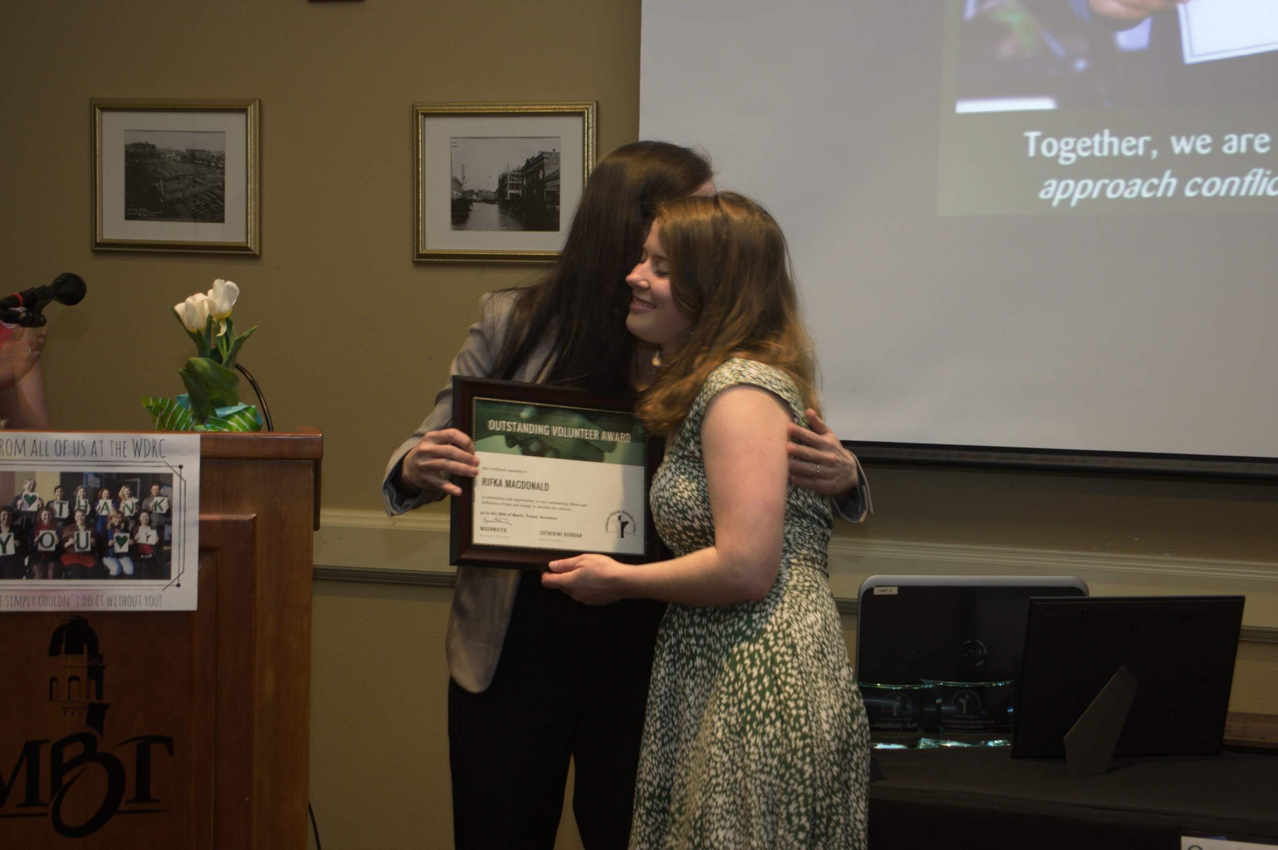 Rifka accepts an award and hug from WDRC Executive Director Moonwater. Photo by Bellingham Photographer Phil Rose.
