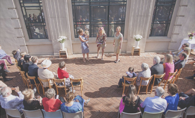 Non traditional Wedding ceremony in bright sunshine, in Wellington Civic square, with the old library building as a backdrop.