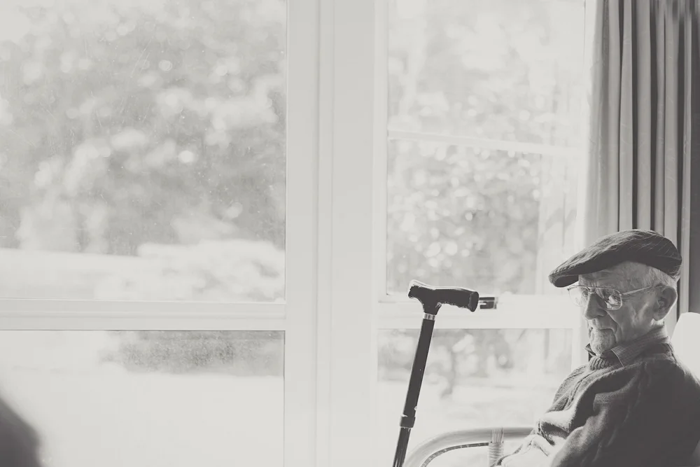 Portrait of a loving grandfather, sitting and contemplating by a window.