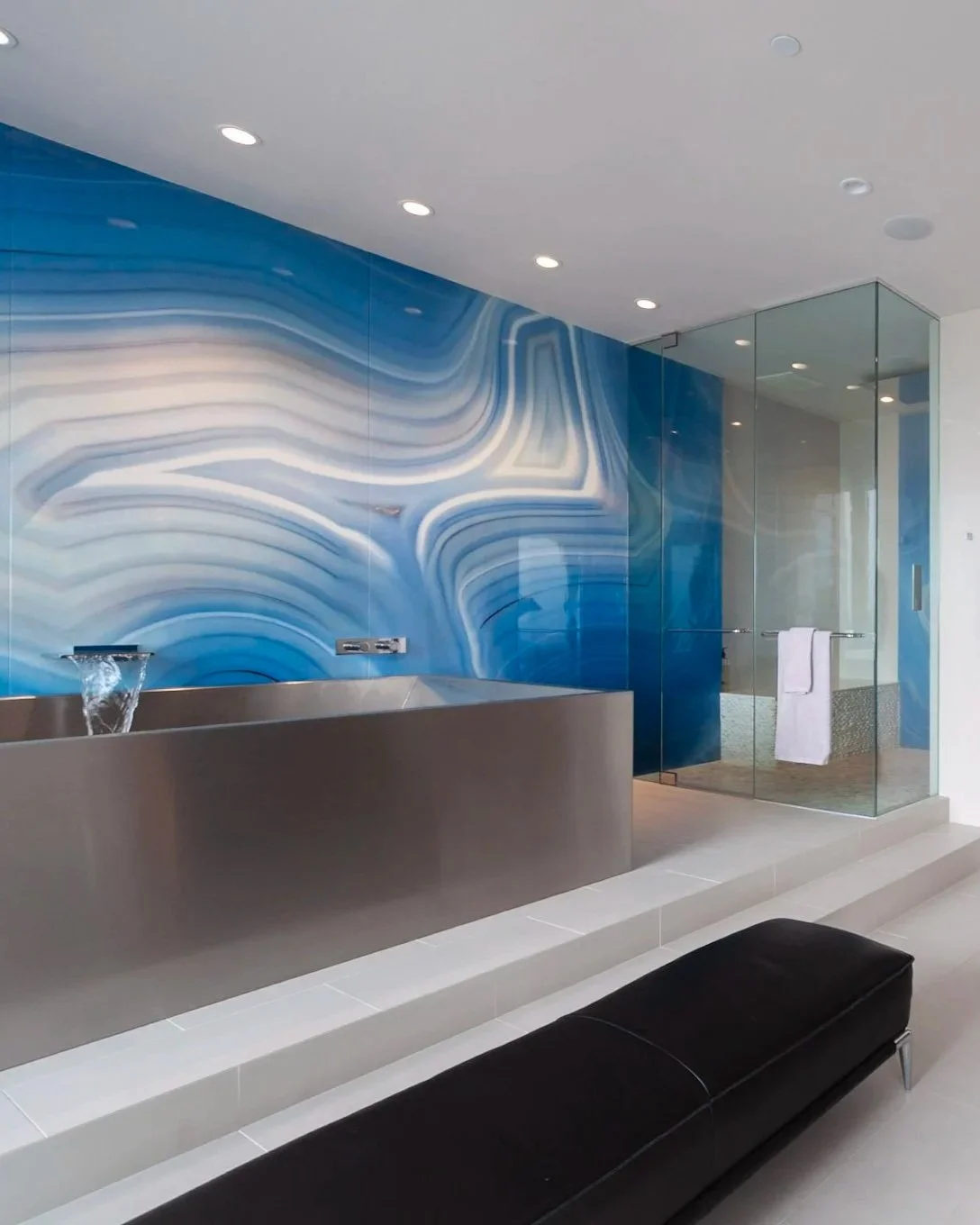 Bathroom with a dramatic blue-and-white stone wall, a rectangular soaking tub, a glass-enclosed shower, and a black bench.